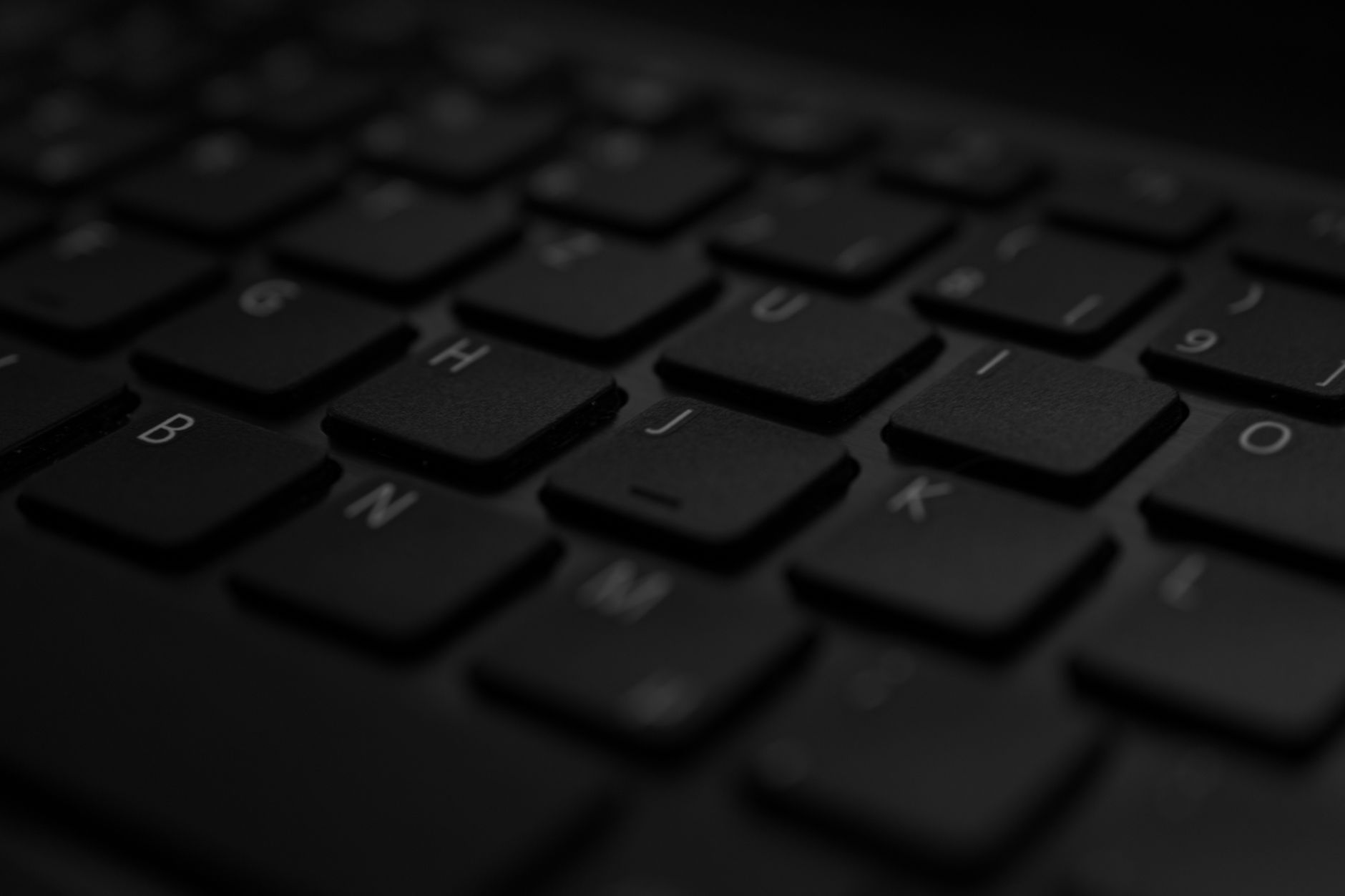 Detailopname van een zwart laptoptoetsenbord met zacht licht en selectieve scherpte.