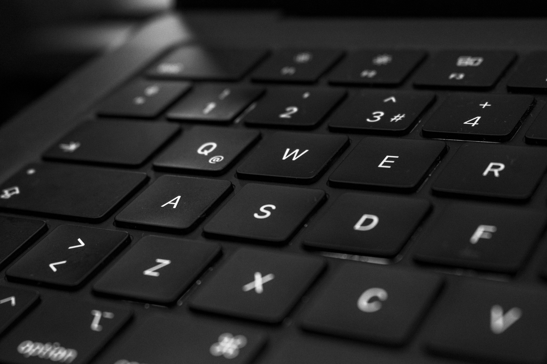 Monochrome close-up van een zwart toetsenbord met focus op de QWER-toetsen.